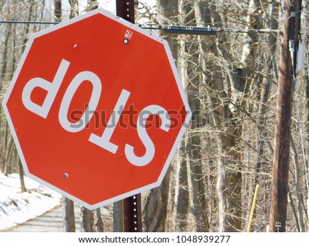 Red Stop Sign Upside Down on Pole on a Country Lane in the Winter Forest
