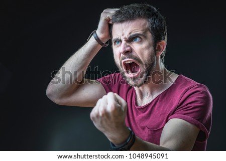 Enraged furious young man screaming in anger, pulling his hair out Royalty-Free Stock Photo #1048945091