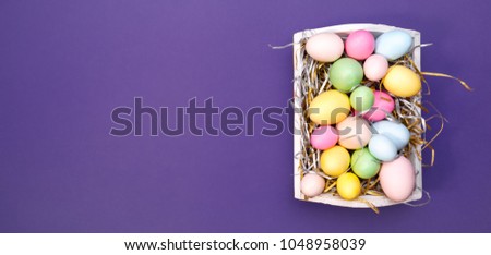 Multicolor eggs in a white tray. Creative Easter concept. Modern solid ultra violet background.  Color of the year inspired. Horizontal, banner wide screen format