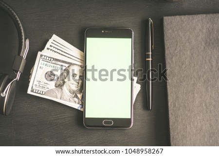 Overhead shot of a male hand using a smart phone with a green screen on a wooden table with a cup of yogurt