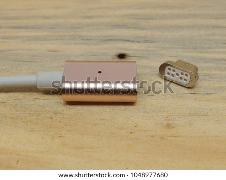 metal rose gold usb data cable charger with magnetic adaptor on wood planks background