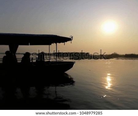 Small boat belong the light of sunset at the lake in silhouette style, unfocused shot.