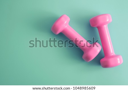 Styled stock photography of fitness equipment dumbbells notepad pencil and earphone on blue background. Flat lay.