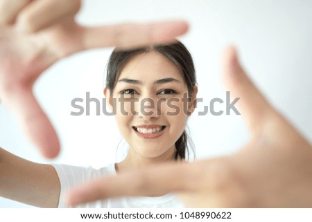 Closeup of Smiling Asian Woman Framing Face with Fingers isolated on white background