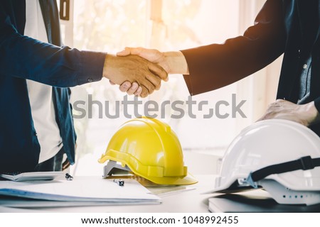 Successful deal, male architect shaking hands with client in construction site after confirm blueprint for renovate building. Royalty-Free Stock Photo #1048992455