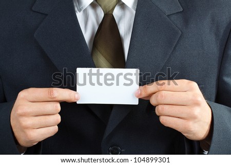 Close-up of a businessman with suit and tie, holding a blank card with both hands, with forefingers and thumbs