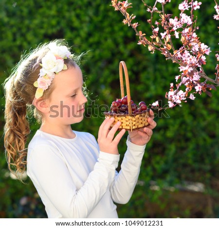 Little happy smiling girl with basket grape in her hands  in summer garden at the sunny day.
