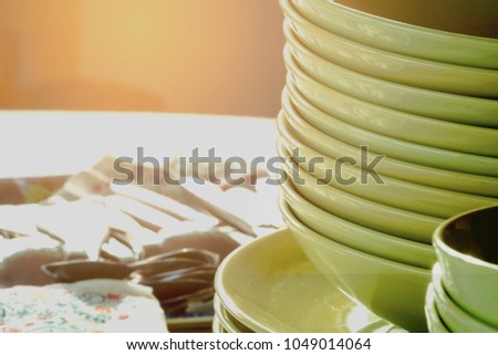 Set of green kitchen plates and forks , spoons organised placed on table . A lot of dishes are collected a bunch. A set of plates gathered together. Household utensils in  the form of tableware. 