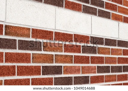 Vintage weathered brick wall background featuring attractive textured bricks in varying hues of red and brown accented with a decorative stripe made of large size white bricks
