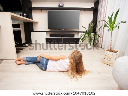 Child watching TV at home. Girl looking at television