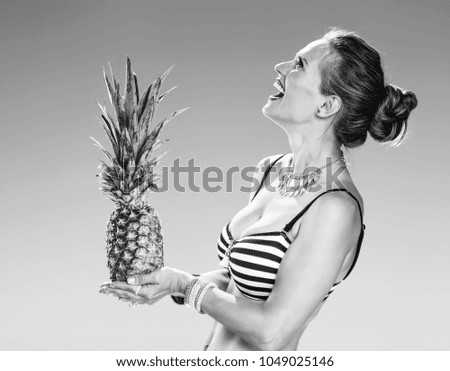 Perfect summer. smiling young woman in beachwear on the seacoast with pineapple looking at copy space