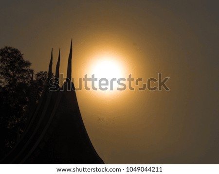 Thai temple roof with the golden sky and the sun before sunset in the evening