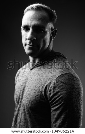 Studio shot of muscular man wearing gray long sleeved hooded shirt in black and white