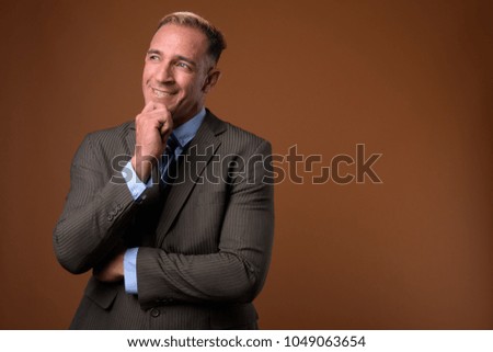 Studio shot of businessman wearing suit against brown background