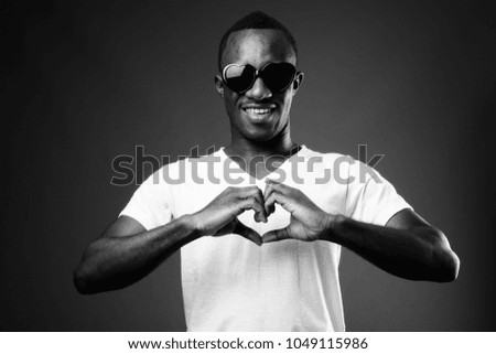 Studio shot of young African man wearing white shirt against black background in black and white