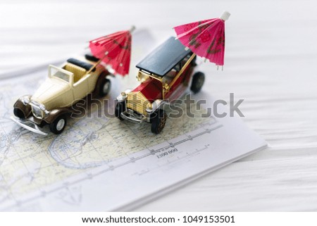 Two small toy cars with beach umbrellas. The concept of travel