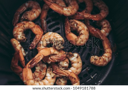Roasted shrimps with garlic and herbs. Seafood, shelfish. Shrimps Prawns grilled with spices and garlic on black stone background, copy space. Shrimps prawns on cast iron pan.
