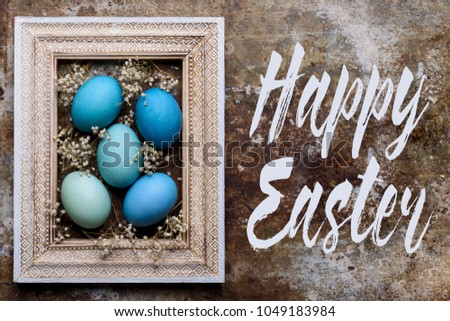 Happy Easter rustic background with copy space. DIY dyed various shades of blue Easter eggs and vintage wooden picture frame mock up.