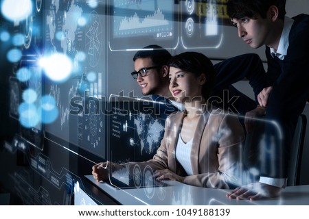 Group of people looking at the futuristic user interface. Royalty-Free Stock Photo #1049188139