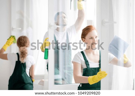 Team of workers cleaning white office windows wearing yellow gloves and protective clothing Royalty-Free Stock Photo #1049209820