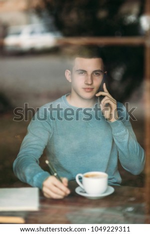 Man uses a laptop in a cafe while drinking coffee