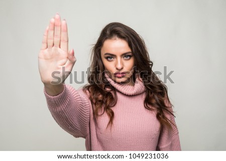 Portrait of a woman standing with outstretched hand showing stop gesture isolated over white background
