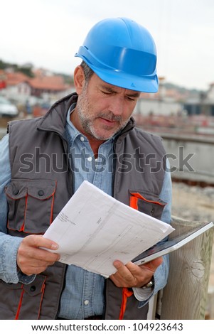 Construction manager controlling building site with plan