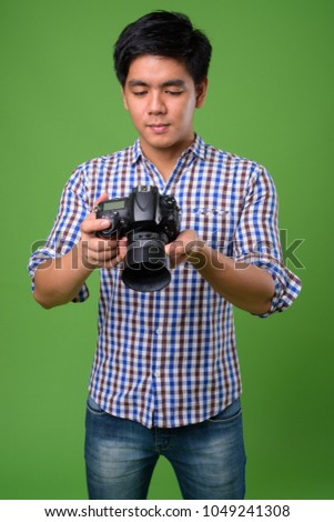 Studio shot of young handsome Filipino man against green background