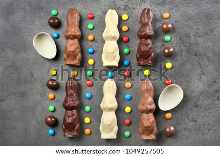 Composition with chocolate Easter bunnies and candies on gray background