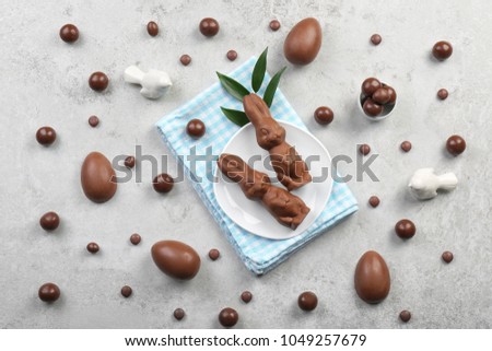 Composition with chocolate Easter bunnies and candies on gray background