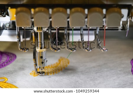 An automatic sewing machine sews with colored threads and precision in making any shape or design. Concept of: automatic, robot, sewing, tailoring, industry.
