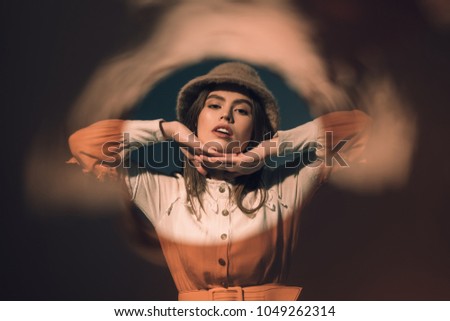 portrait of fashionable young woman in hat looking at camera