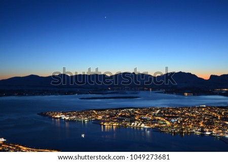 TROMSO, NORWAY - MARCH 6, 2017: The northern lights (Aurora Borealis) and the city scape from Fjellheisen Peak over the city 