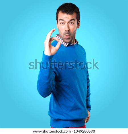 Handsome young man making OK sign on colorful background