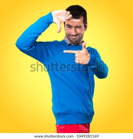 Handsome young man focusing with his fingers on colorful background