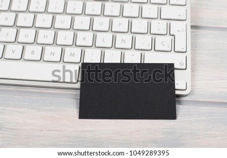Business card in black color on computer keyboard. Mockup.