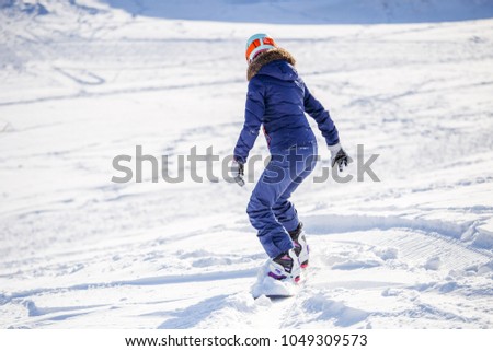Photo from back of woman snowboarding