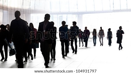 People walking against the light background of an urban landscape. Silhouettes.