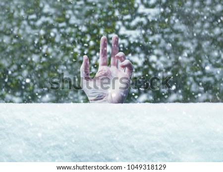 Man buried in deep freezing cold crisp snow with just his hand sticking through during a blizzard or snowstorm possibly suffering hypothermia.