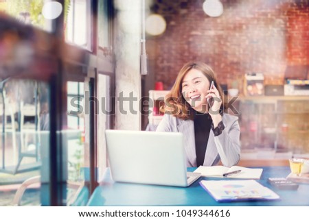 Smiling Business woman working in office with documents,Happy Asian businesswoman using phone sitting on chair at  modern home studio.Concept of young people working mobile devices,contact to costumer