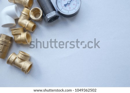 Various plumbers tools and plumbing materials including stainless steel, plastic and copper pipe, elbow joint, wrench and spanner. White background. Top view, copyspace