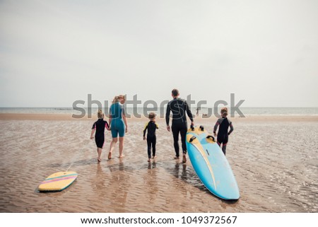 Family walking to the water's edge to go surfing.
