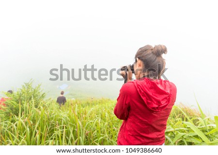 Traveller standing and take photo on a hill in the morning with foggy view and rain