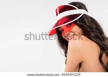 attractive tanned girl posing in red visor, isolated on white