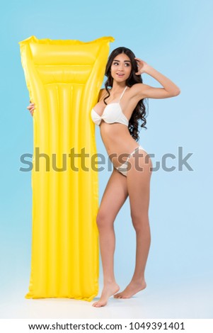 beautiful young woman with yellow inflatable mattress, isolated on blue