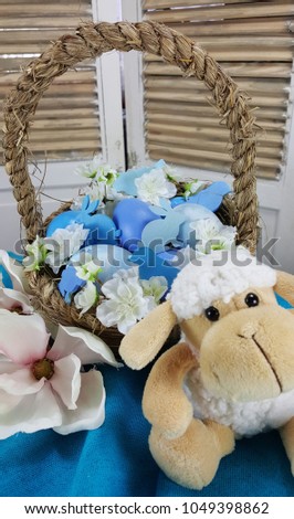 Easter  decoration - basket with blue eggs, flowers of apple tree,  birds and bunnies of them on blue tablecloth.
Easter background.