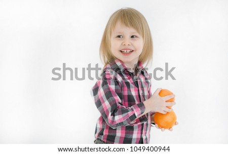 Copy space.Emotional portrait of positive and happy little girl with blond hair looking with a smile to the side holding in hands two oranges isolated on white background