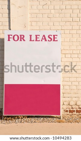 For lease sign against a neutral brick wall