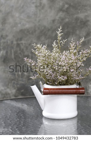 Purple dry flower in white vase on glass table.