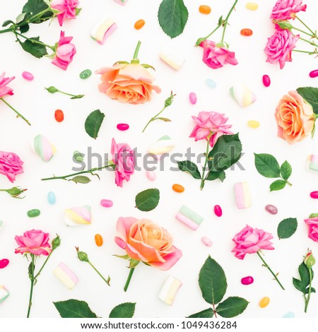Floral pattern with roses, buds, leaves and marshmallow with candy on white background. Flat lay, top view. Spring background